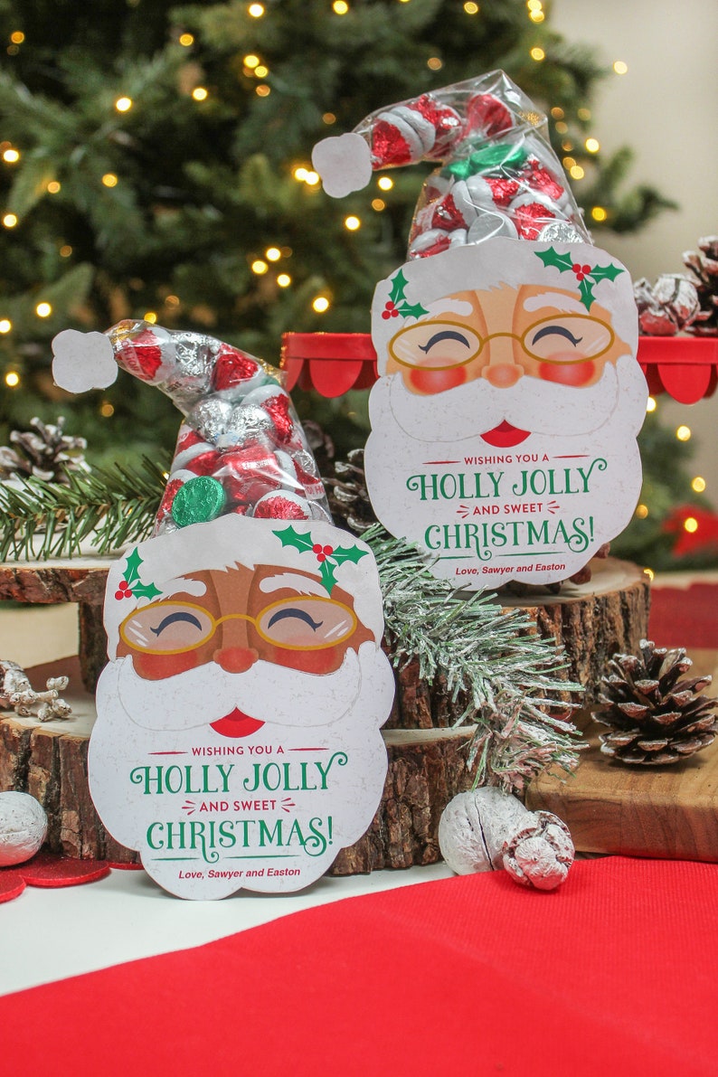 May include: Two festive Santa Claus gift bags with a red and white candy cane design. Each bag is filled with chocolate candies and has a message that reads "Wishing you a Holly Jolly and Sweet Christmas! Love, Sawyer and Easton".