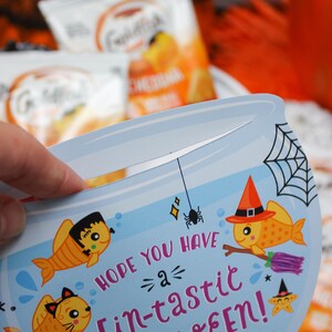 May include: A blue and orange Halloween card shaped like a fishbowl with a goldfish wearing a witch's hat and holding a broom. The card says "Hope you have a fin-tastic Halloween!" and is signed "Love, Easton".