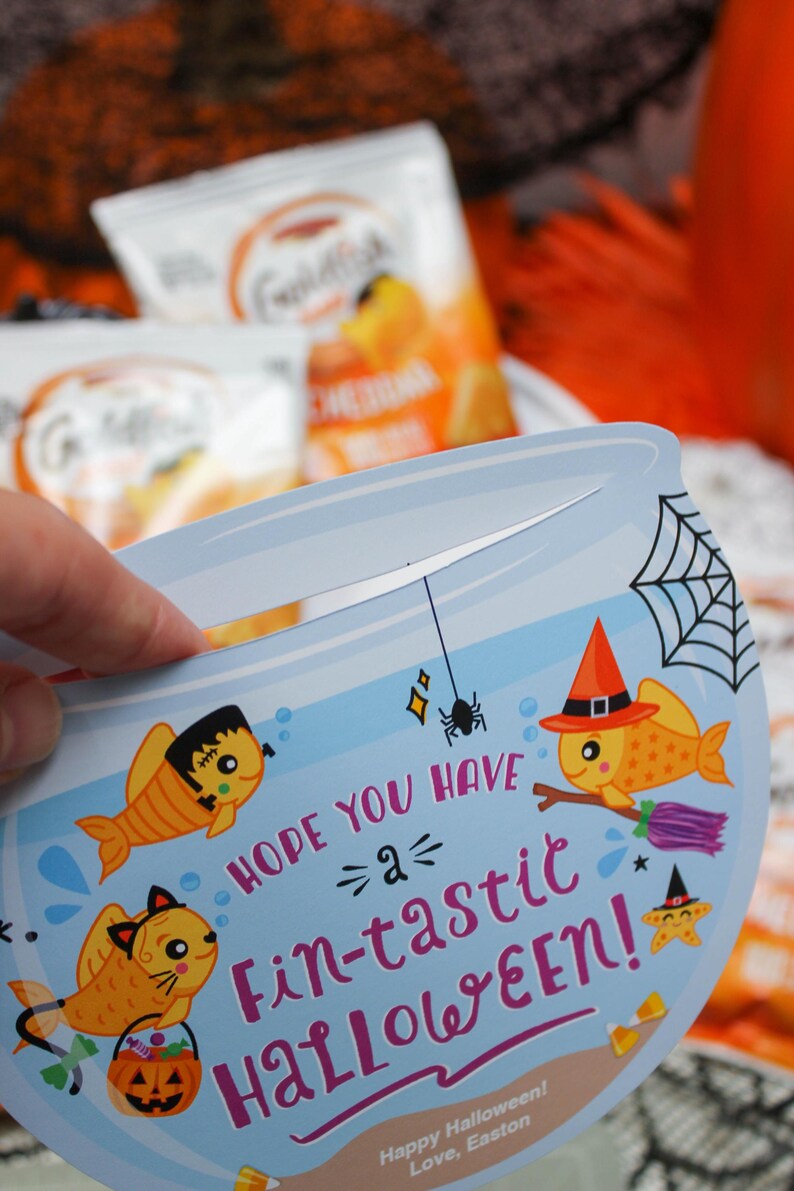 May include: A blue and orange Halloween card shaped like a fishbowl with a goldfish wearing a witch's hat and holding a broom. The card says "Hope you have a fin-tastic Halloween!" and is signed "Love, Easton".