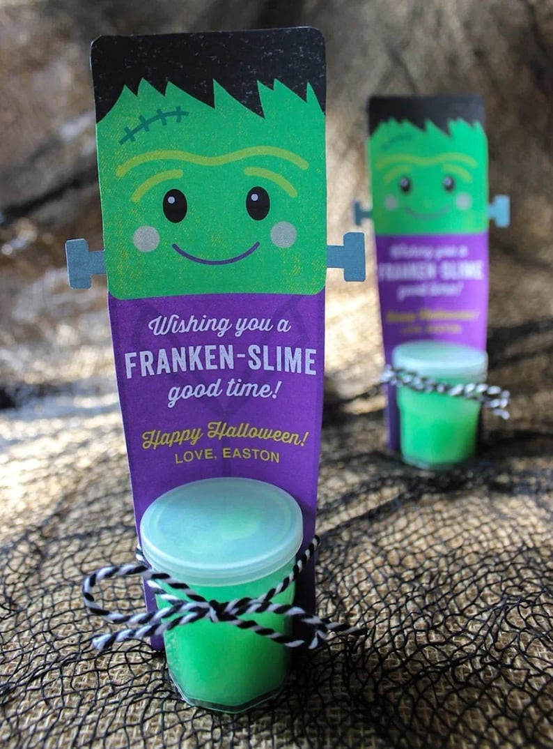 Puede incluir: Un monstruo de Frankenstein verde con un fondo morado y el texto "Wishing you a FRANKEN-SLIME good time! Happy Halloween! LOVE, EASTON" est&aacute; unido a un peque&ntilde;o frasco transparente con slime verde en su interior.