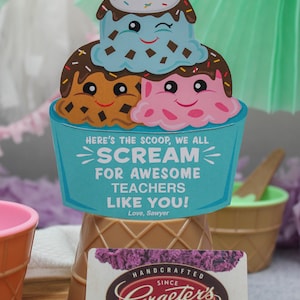 Puede incluir: Un cono de helado azul y blanco con tres bolas de helado. Las bolas de helado tienen caras y chispas. El cono est&aacute; sobre una superficie de madera con una tarjeta de regalo para Graeter's Ice Cream. La tarjeta de regalo tiene un cono de helado morado con una bola de helado en la parte superior. El texto de la tarjeta de regalo dice "Handcrafted Since 1870 Graeter's Ice Cream Gift Card".
