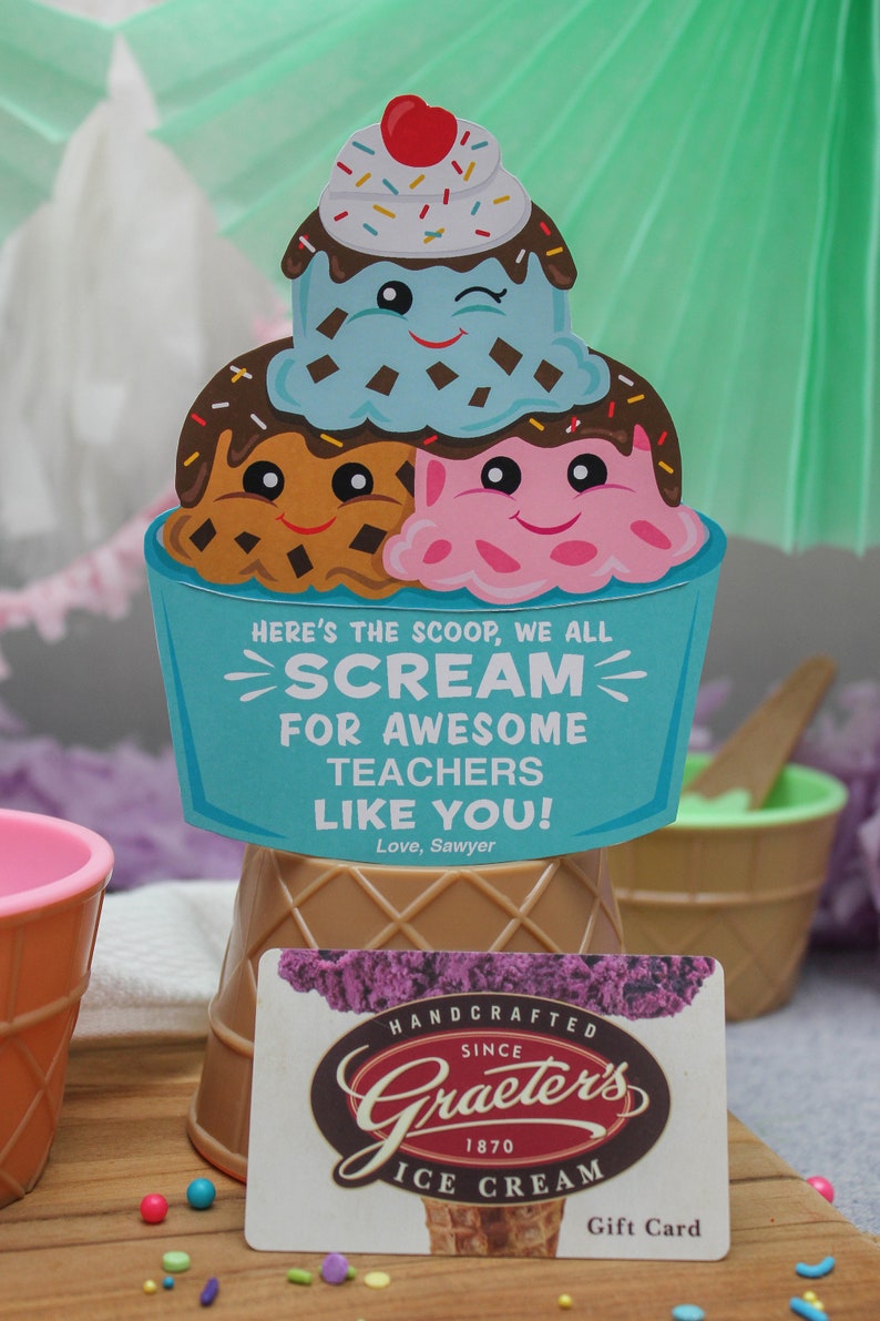 Puede incluir: Un cono de helado azul y blanco con tres bolas de helado. Las bolas de helado tienen caras y chispas. El cono est&aacute; sobre una superficie de madera con una tarjeta de regalo para Graeter's Ice Cream. La tarjeta de regalo tiene un cono de helado morado con una bola de helado en la parte superior. El texto de la tarjeta de regalo dice "Handcrafted Since 1870 Graeter's Ice Cream Gift Card".