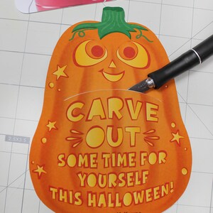 May include: Orange pumpkin-shaped card with a smiling jack-o'-lantern face and the text "Carve out some time for yourself this Halloween! Love, The McKowns".