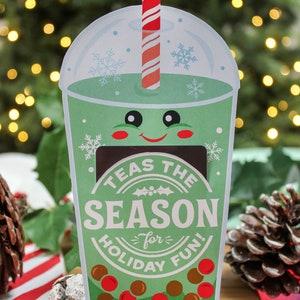 Pode incluir: Um cart&atilde;o de Natal verde e branco em forma de copo de boba com um canudo vermelho e branco listrado. O cart&atilde;o diz "Tea's the Season for Holiday Fun!" e "Love, The McKown Family".