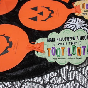 May include: Orange and green Halloween party favour with a pumpkin face and the text "Make Halloween a Hoot with this Toot Loot! Happy Halloween! Your Friend, Sawyer".