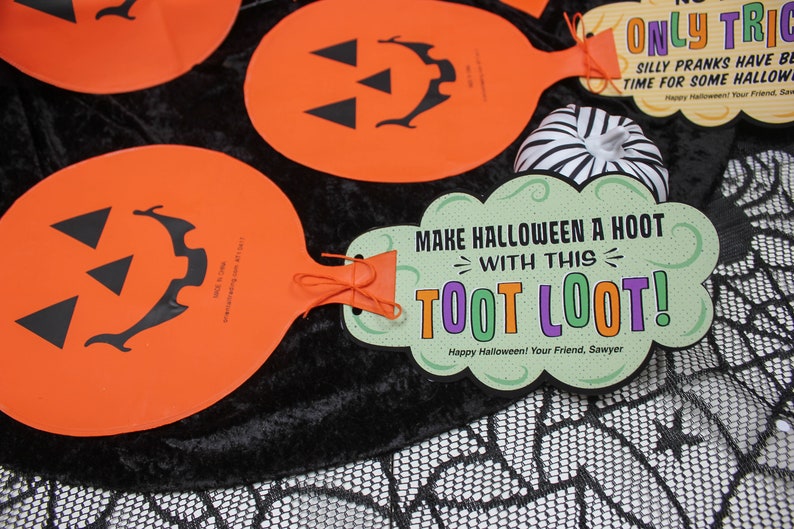 May include: Orange and green Halloween party favour with a pumpkin face and the text "Make Halloween a Hoot with this Toot Loot! Happy Halloween! Your Friend, Sawyer".