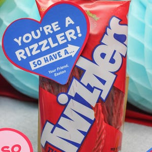 May include: A red bag of Twizzlers candy with a blue heart-shaped tag that says "You're a rizzler! So have a... Your Friend, Easton".