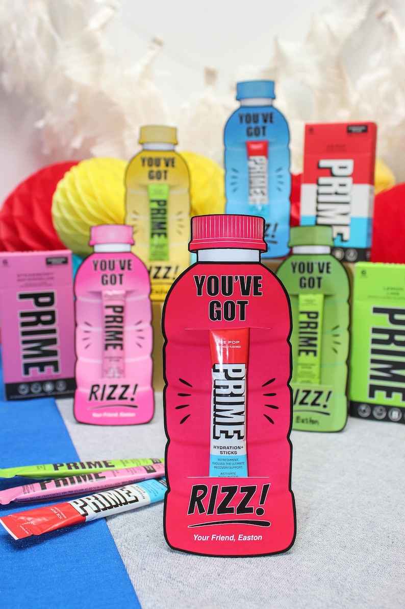 May include: A pink, red and blue Prime Hydration stick with the text "You've Got Prime" and "Rizz! Your Friend, Easton" on a pink and red bottle-shaped card. The card is surrounded by other Prime Hydration bottles and boxes.