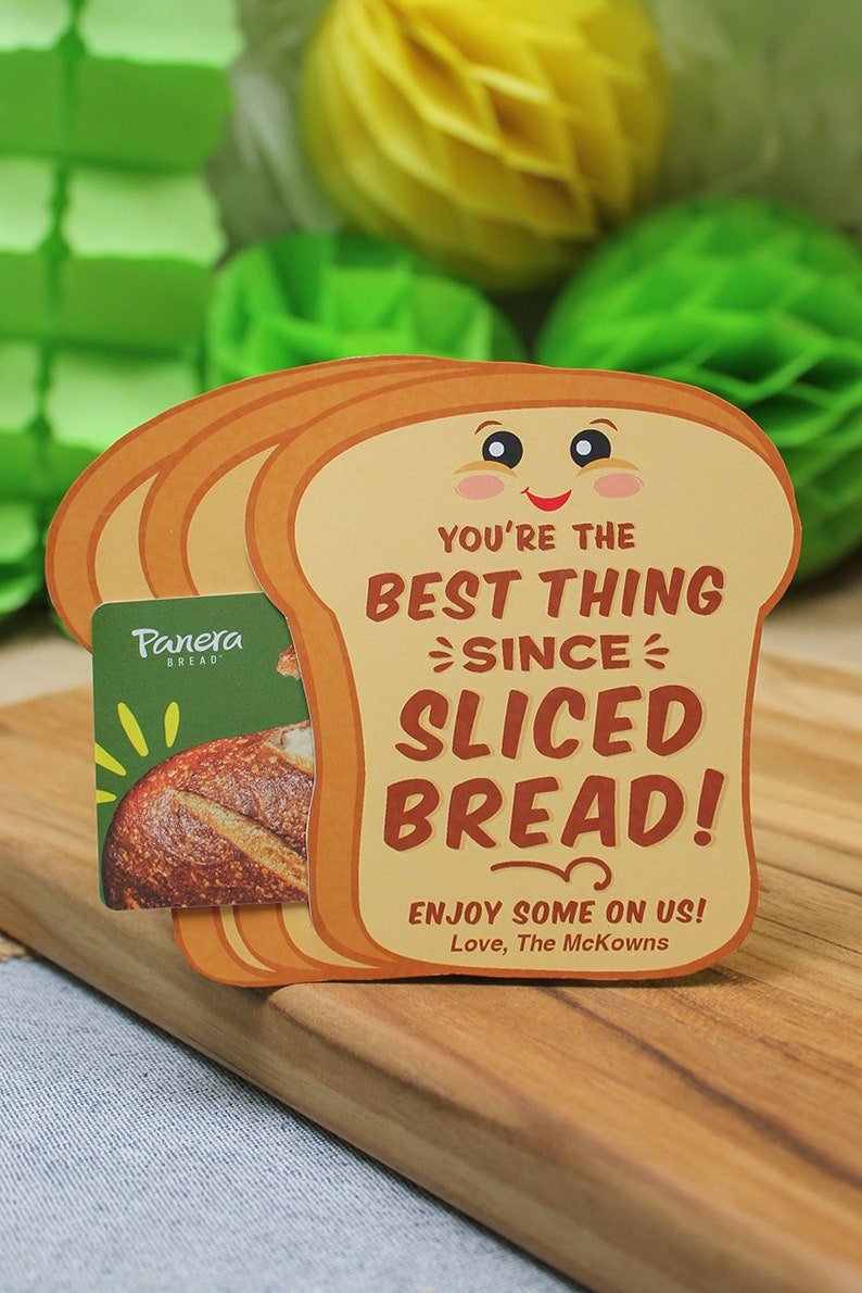 May include: A brown and yellow card shaped like a slice of bread with the text "You're the best thing since sliced bread!" and "Enjoy some on us! Love, The McKowns". A Panera Bread gift card is partially visible behind the card.
