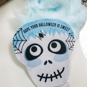 Puede incluir: Una tarjeta de Halloween azul y blanca con una cara de calavera de dibujos animados y el texto "Espero que tu Halloween sea dulce. Con cari&ntilde;o, Sawyer & Easton".