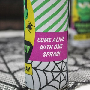May include: A green and white striped can with a pink label that says "Come alive with one spray!" The can has a spider on it and a black and white spiderweb design.