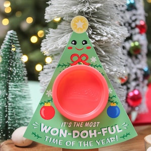 May include: A Christmas-themed card with a Play-Doh container in the center. The card is shaped like a green Christmas tree with a red bow and a star on top. The text on the card reads "It's the most Won-Doh-ful time of the year!" and "Your Friend, Easton".