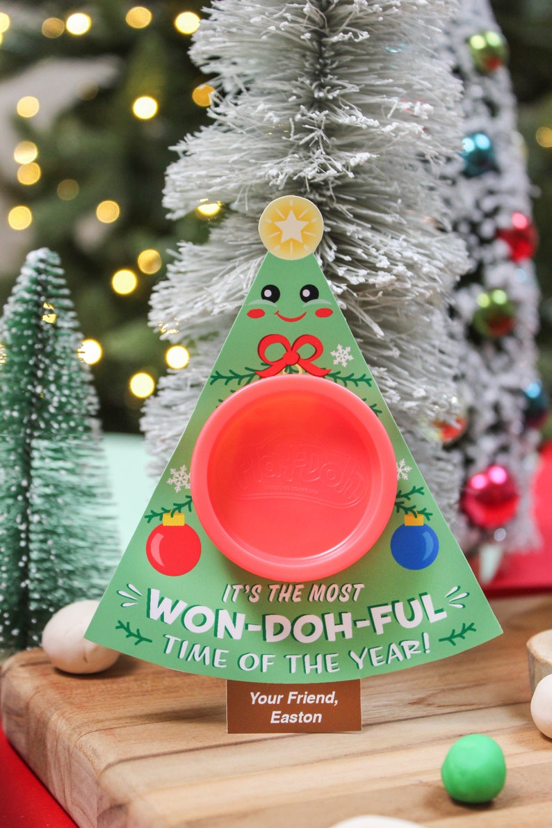 May include: A Christmas-themed card with a Play-Doh container in the center. The card is shaped like a green Christmas tree with a red bow and a star on top. The text on the card reads "It's the most Won-Doh-ful time of the year!" and "Your Friend, Easton".