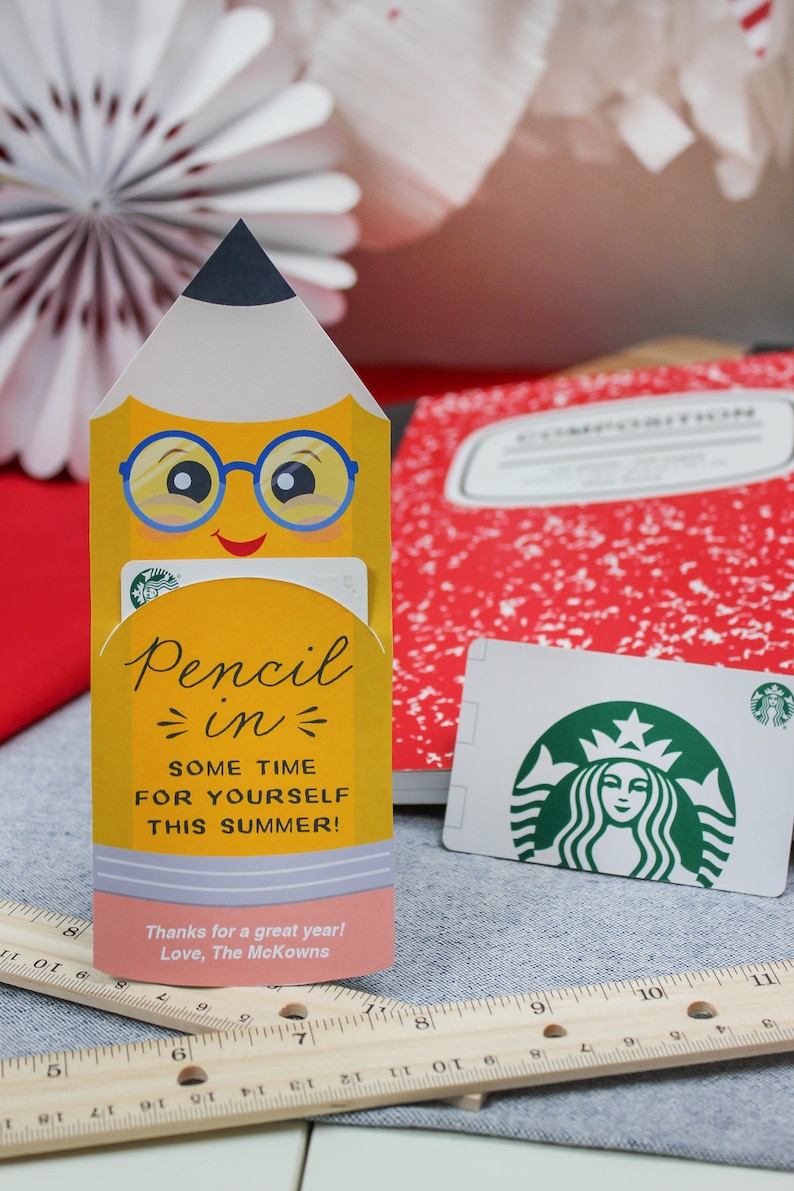 May include: A yellow pencil-shaped gift card holder with a smiling face and blue glasses. The holder says "Pencil in some time for yourself this summer!" and holds a Starbucks gift card. A red composition notebook is in the background.