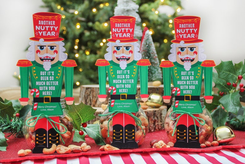 May include: Three nutcracker-themed gift jars filled with mixed nuts. Each jar has a red and green nutcracker cutout with the text "Another Nutty Year" and "But it's been so much better with you here!"  Merry Christmas! Love, Alison.