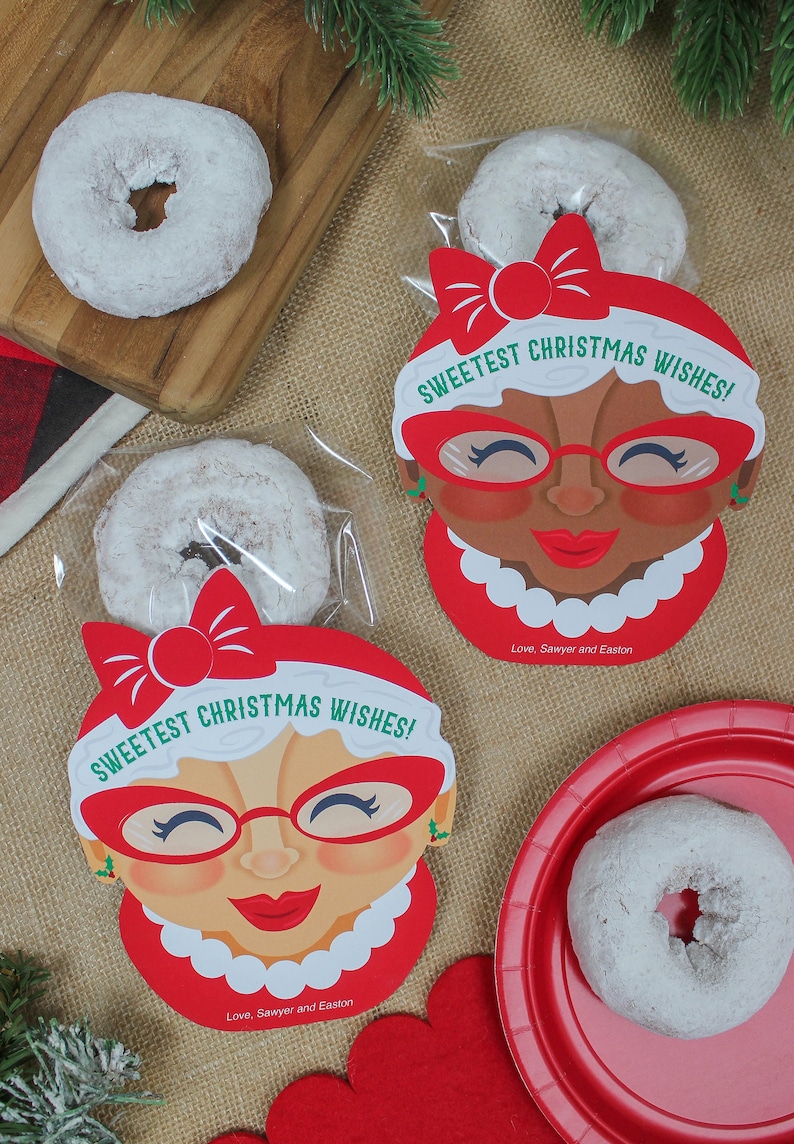 May include: Two red and white Christmas gift bags with a donut inside. The bags feature a cartoon woman with red glasses and the text "Sweetest Christmas Wishes!" and "Love, Sawyer and Easton".