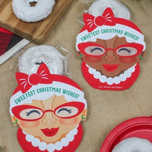 May include: Two red and white Christmas gift tags featuring a cartoon woman wearing glasses and a red bow. The tags read "Sweetest Christmas Wishes!" and "Love, Sawyer and Easton".