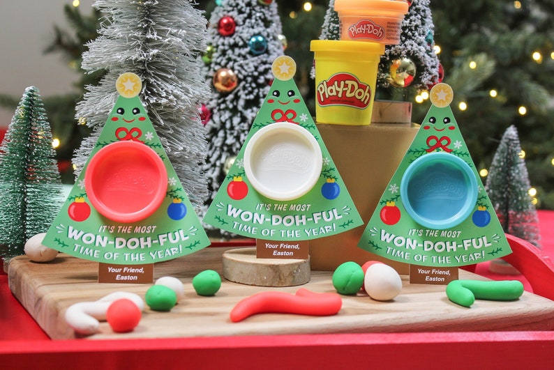 May include: Three Christmas tree-shaped Play-Doh containers with the text "It's the most Won-Doh-Ful Time of the Year!" and a Play-Doh container with the text "Play-Doh" on it.