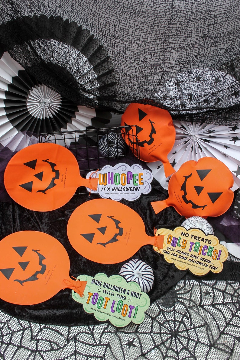 May include: A set of orange and black Halloween party decorations featuring pumpkin-shaped blow-up toys with smiling faces and a variety of signs with Halloween-themed messages. The signs say "Whoopie! It's Halloween!" and "No Treats Only Tricks! Silly Pranks Have Begun... Time For Some Halloween Fun!" and "Make Halloween A Hoot With This Toot Loot!"