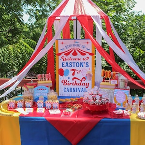 Peut inclure: D&eacute;coration de f&ecirc;te d'anniversaire sur le th&egrave;me du carnaval, avec des couleurs rouge, blanc et bleu. La table est orn&eacute;e de pop-corn, de petits g&acirc;teaux et d'une pancarte indiquant "Bienvenue au 7e anniversaire de carnaval d'Easton". Une structure de tente &agrave; rayures rouges et blanches est au-dessus.