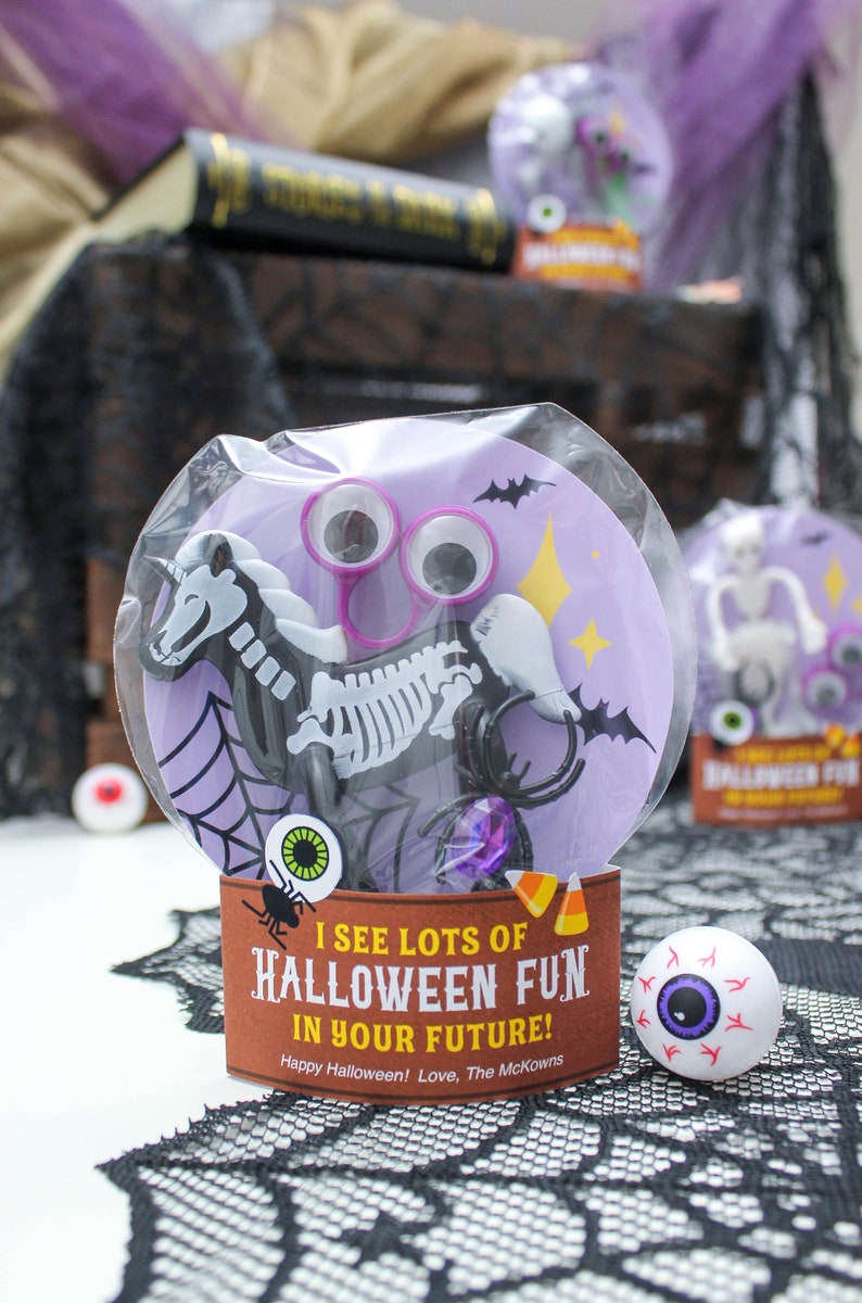 May include: A purple and white Halloween party favor bag with a skeleton horse, googly eyes, and a spider. The bag has a tag that says "I see lots of Halloween fun in your future! Happy Halloween! Love, The McKowns".