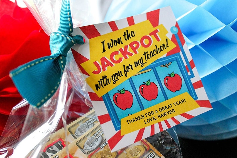 May include: A yellow and red gift tag with the text "I won the JACKPOT with you for my teacher!" and a slot machine graphic with three red apples. The text "THANKS FOR A GREAT YEAR! LOVE, SAWYER" is at the bottom of the tag.