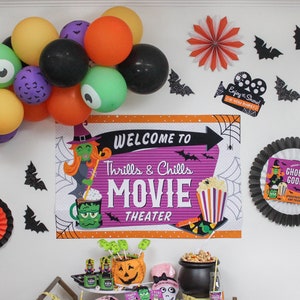 May include: Halloween movie night party decorations with a purple and orange banner that says "Welcome to Thrills & Chills Movie Theater", black bats, orange and black paper fans, and a witch and monster themed balloon arch.