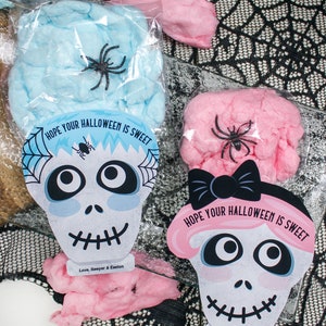 Puede incluir: Dos bolsas de pl&aacute;stico transparentes llenas de algod&oacute;n de az&uacute;car rosa y azul. Cada bolsa tiene una tarjeta impresa con un dise&ntilde;o de calavera y el texto "Espero que tu Halloween sea dulce." y "Con cari&ntilde;o, Sawyer & Easton".