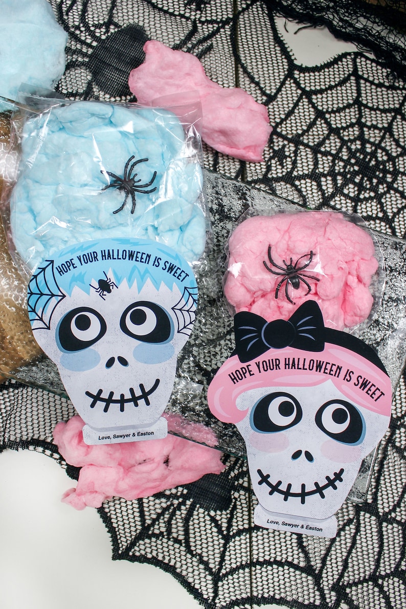 Puede incluir: Dos bolsas de pl&aacute;stico transparentes llenas de algod&oacute;n de az&uacute;car rosa y azul. Cada bolsa tiene una tarjeta impresa con un dise&ntilde;o de calavera y el texto "Espero que tu Halloween sea dulce." y "Con cari&ntilde;o, Sawyer & Easton".