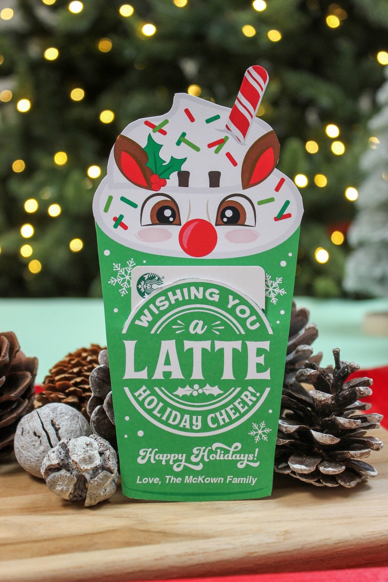 Puede incluir: Una tarjeta de Navidad verde y blanca con forma de taza de caf&eacute; con una cara de reno y el texto "Wishing you a latte holiday cheer! Happy Holidays! Love, The McKown Family."