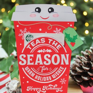 Pode incluir: Porta-cart&atilde;o de presente de Natal vermelho e branco em forma de x&iacute;cara de caf&eacute; com o texto "Tea's the Season for Warm Holiday Wishes" e "Happy Holidays! Love, The McKown Family".