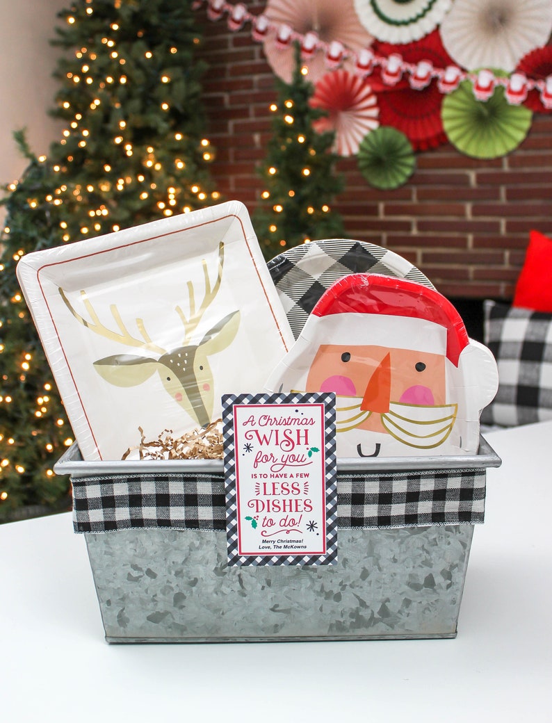 May include: A metal container with a black and white checkered ribbon around the top. Inside the container are paper plates with a reindeer and Santa Claus design. A gift tag with the text "A Christmas Wish for you is to have a few less dishes to do! Merry Christmas! Love, The McKeown" is attached to the container.