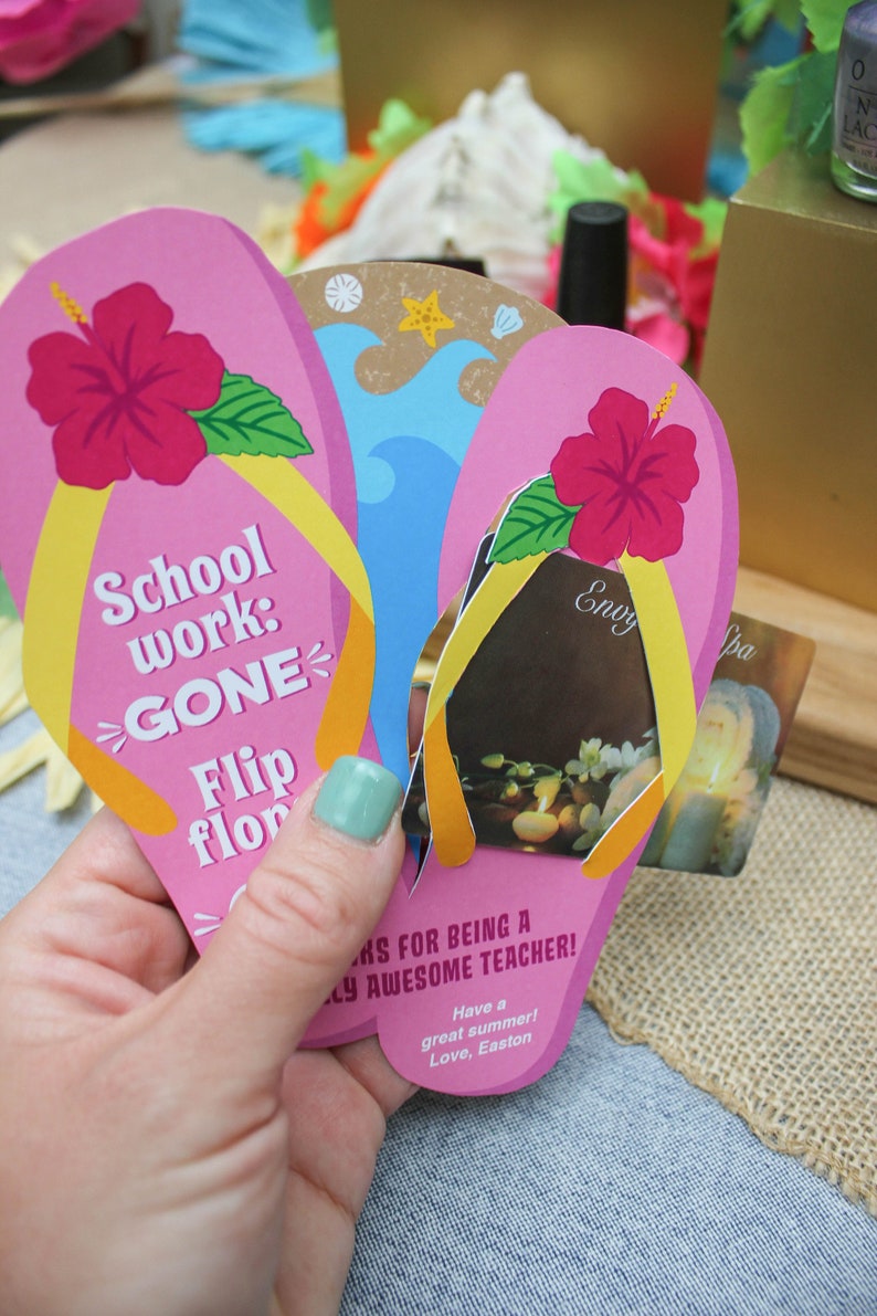 May include: Pink and yellow flip-flop shaped card with the text "School work: GONE Flip flop" and a hibiscus flower. The card is being held in a hand and has a gift card tucked inside. The gift card is for a spa and has the text "Envy Spa" on it.