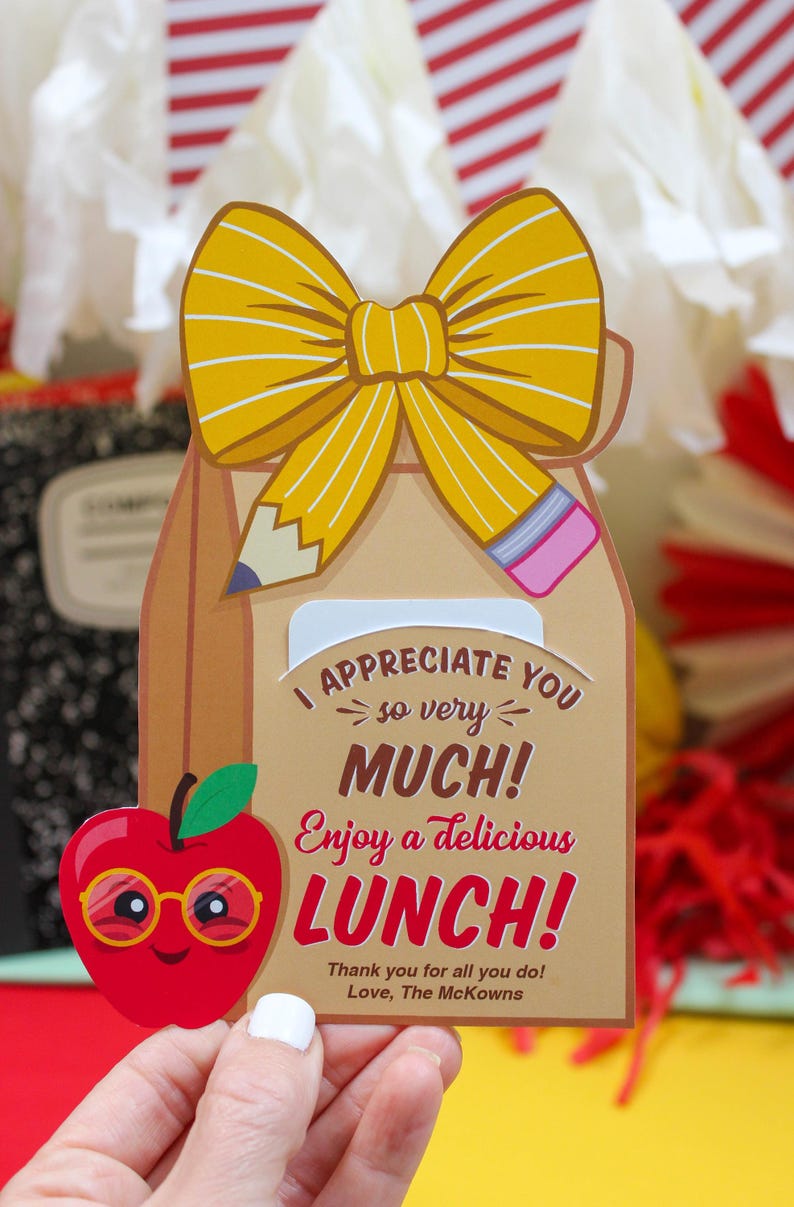 May include: A brown paper lunch bag with a yellow bow and a red apple with glasses. The bag has a message that says "I appreciate you so very much! Enjoy a delicious lunch! Thank you for all you do! Love, The McKowns"