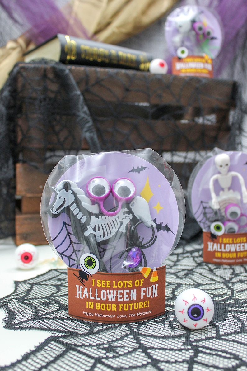 May include: A purple and black Halloween party favor bag with a skeleton unicorn toy, googly eyes, and a spider. The bag has a brown label that says "I see lots of Halloween fun in your future! Happy Halloween! Love, The McKowns".