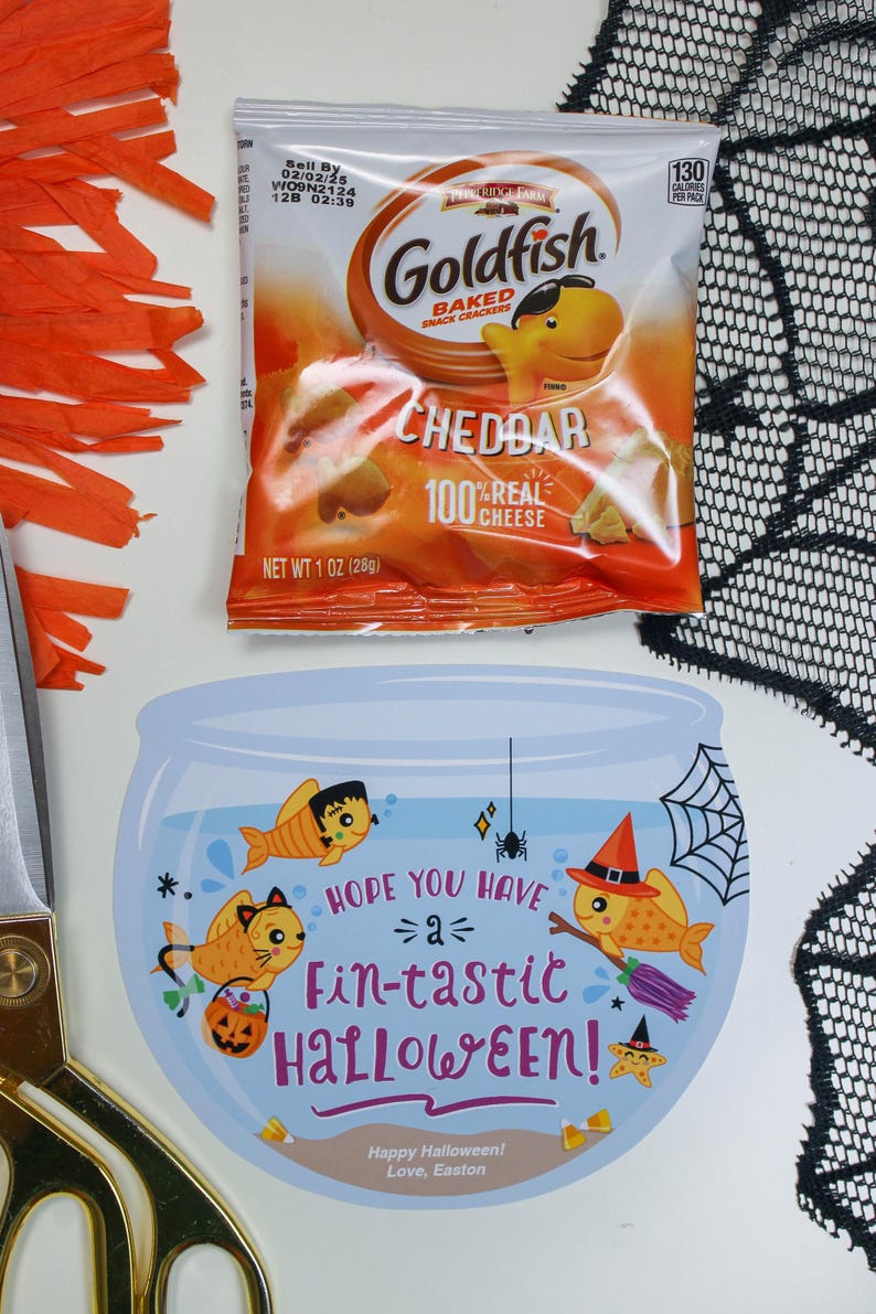 May include: A blue and white card with a goldfish bowl illustration. Three goldfish are inside the bowl, one wearing a witch's hat, one wearing a cat costume, and one wearing a Frankenstein costume. The card says "Hope you have a fin-tastic Halloween!" and "Happy Halloween! Love, Easton".