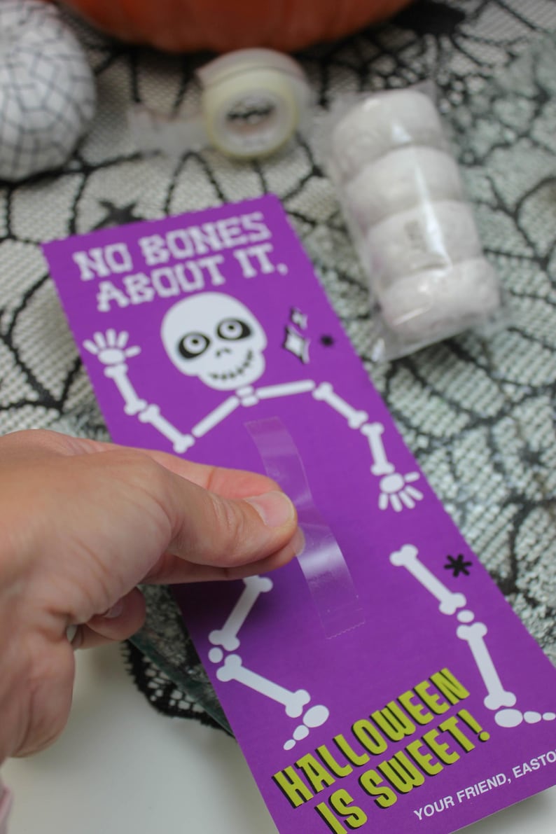 May include: Purple card with a skeleton illustration and the text "No bones about it. Halloween is sweet!"  The card has a clear adhesive strip on the back.