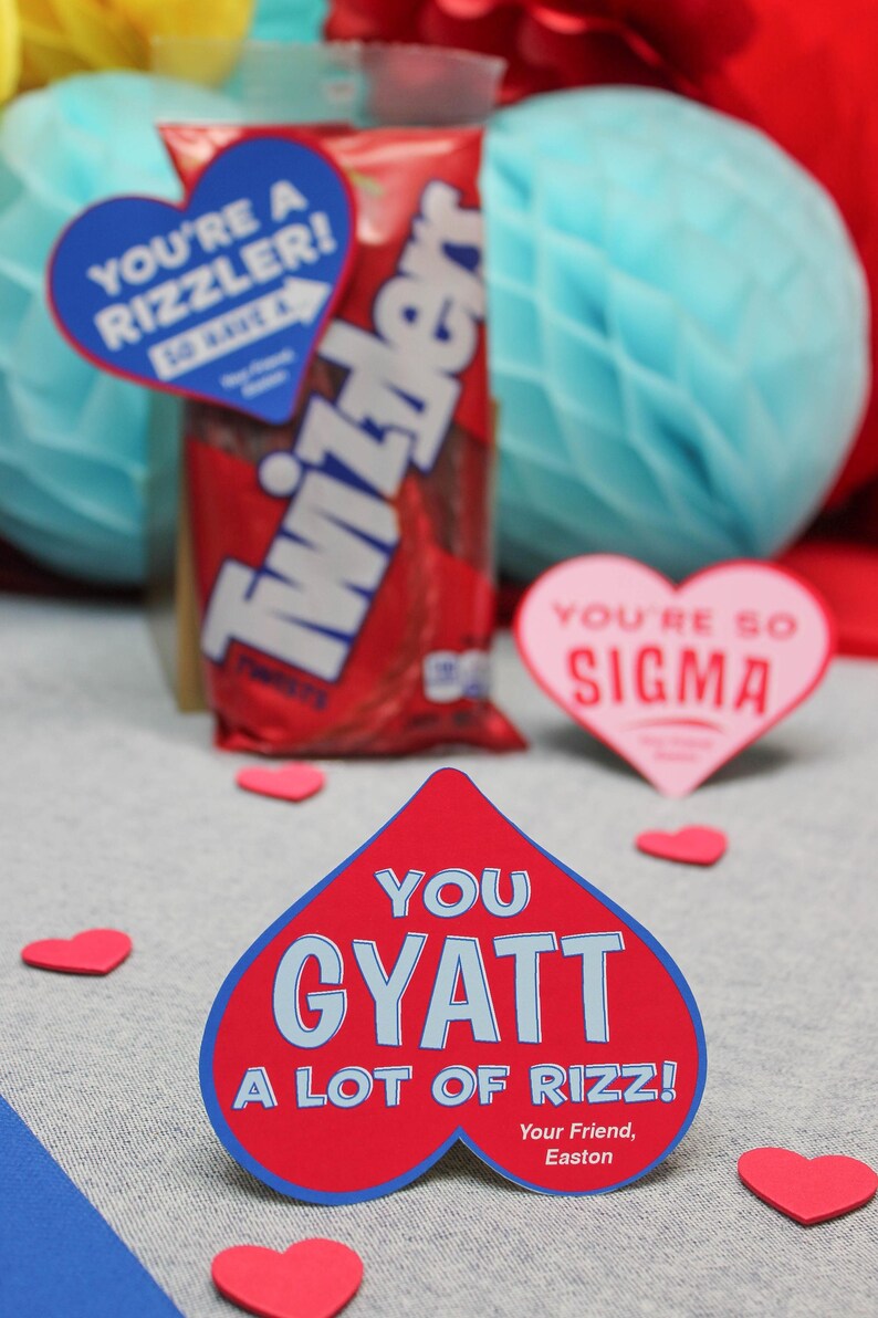 May include: Red heart-shaped card with blue text that reads "You Gyatt A Lot Of Rizz!" with the text "Your Friend, Easton" at the bottom. The card is surrounded by small red hearts.