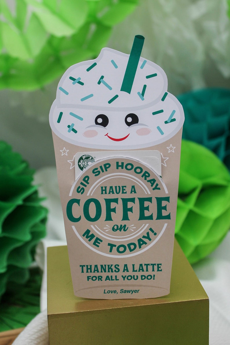 May include: A brown and white coffee cup with a smiling face and sprinkles on top. The cup has a green straw and text that says "Sip Sip Hooray Have a Coffee on Me Today! Thanks a Latte for all you do! Love, Sawyer".
