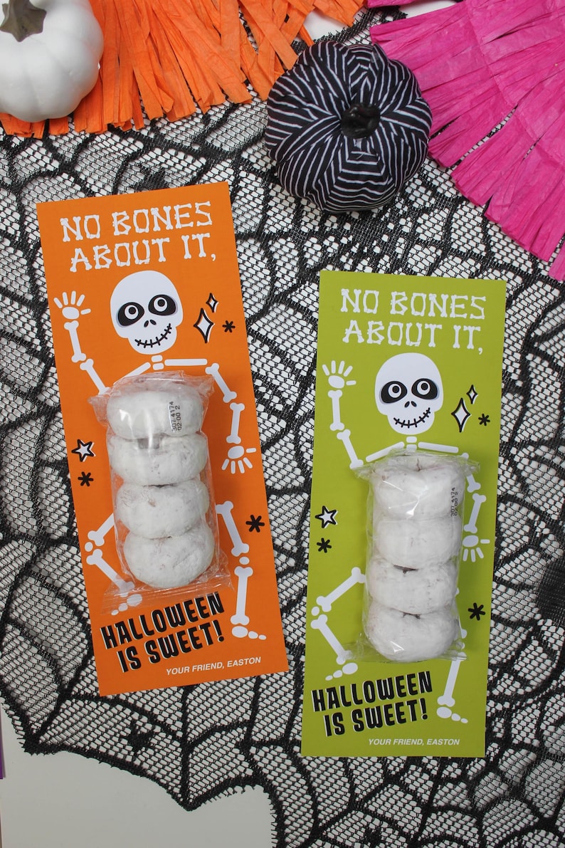 May include: Two Halloween treat bags with a skeleton design and the text "No bones about it, Halloween is sweet!"  Each bag contains a stack of mini donuts.