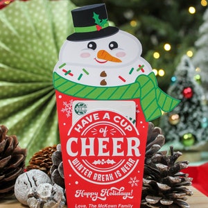 Puede incluir: Un porta tarjetas de regalo con forma de mu&ntilde;eco de nieve rojo y blanco con el texto "Have a Cup of Cheer Winter Break is Near" y "Happy Holidays! Love, The McKown Family".