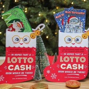 Pode incluir: Dois cart&otilde;es de Natal em forma de meia vermelha e branca com um rosto sorridente, &oacute;culos e sinos. Cada cart&atilde;o tem o texto "Na esperan&ccedil;a de que um Lotto Cash chegue em breve!" e um bilhete de loteria dentro.