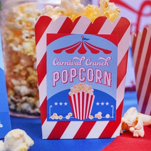 May include: Red and white striped popcorn box with a blue and red circus tent design. The box has a label that says "Carnival Crunch Popcorn".