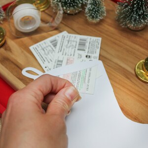 Pode incluir: Uma meia branca com uma etiqueta de presente verde e branca anexada. A etiqueta tem o texto "1812-0027820-00".