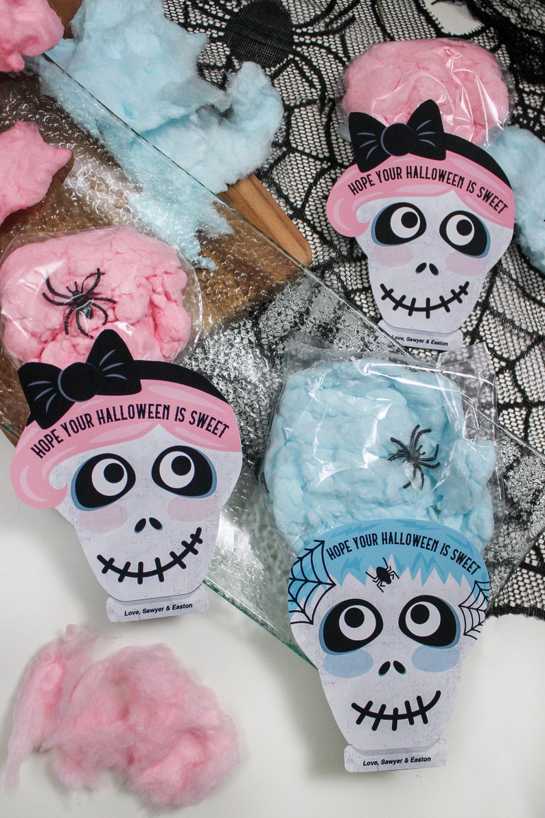Puede incluir: Cuatro bolsas de algod&oacute;n de az&uacute;car rosa y azul con una etiqueta en forma de calavera unida a cada bolsa. Las etiquetas tienen un lazo negro, una ara&ntilde;a y el texto "Espero que tu Halloween sea dulce".