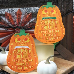 May include: Two orange pumpkin-shaped cards with a cut-out slot for a gift card. The cards have a smiling pumpkin face and the text "CARVE OUT SOME TIME FOR YOURSELF THIS HALLOWEEN! Love, The McKowns".