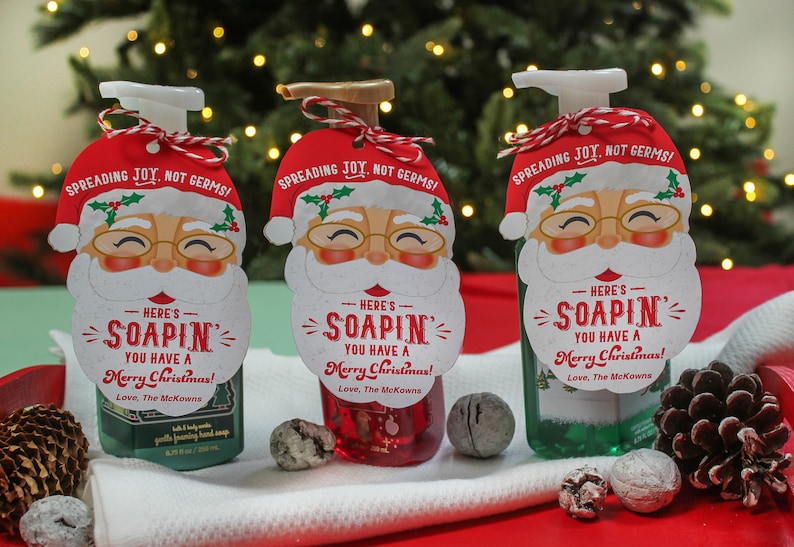 Op de afbeelding: Drie groene flessen vloeibare handzeep met rode en witte kerstman-cadeautjeslabels. De labels zeggen "Here's Soapin' You Have a Merry Christmas! Love, The McKowns".