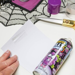 May include: A can of purple grape flavored "Sented Silly Dreamers" party time silly spray. The can has a cartoon grape character with a big smile and a purple hat. The can is on a white surface.