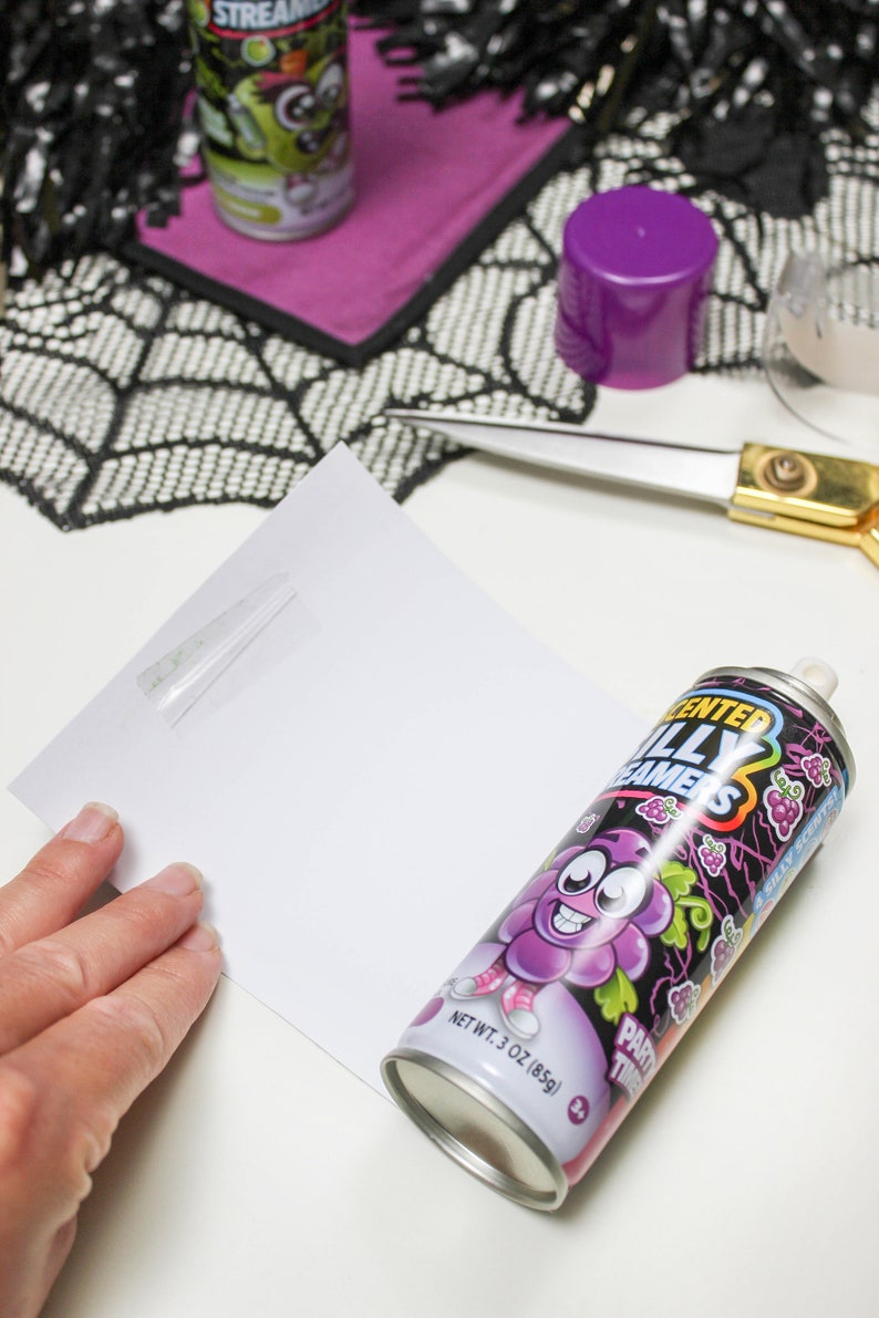May include: A can of purple grape flavored "Sented Silly Dreamers" party time silly spray. The can has a cartoon grape character with a big smile and a purple hat. The can is on a white surface.