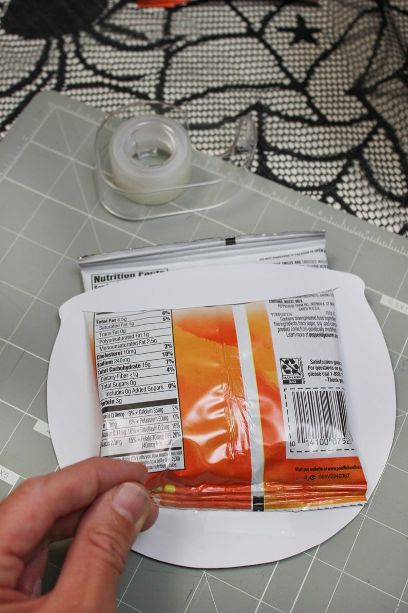 May include: A close-up of a bag of chips with a nutrition facts label. The label lists the total fat, saturated fat, trans fat, polyunsaturated fat, monounsaturated fat, cholesterol, sodium, total carbohydrate, dietary fiber, total sugars, and protein per serving. The bag is on a white surface.